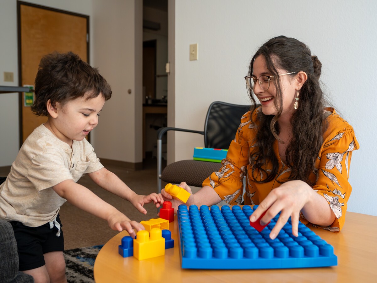 An adult and child build with colorful blocks at a table.