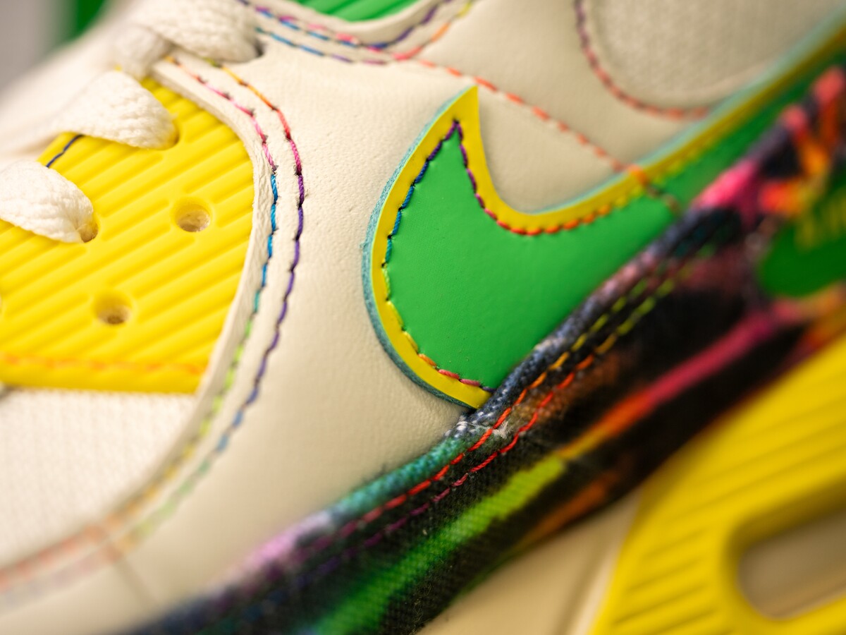 Bright stitching and layered materials detail a colorful Nike shoe.