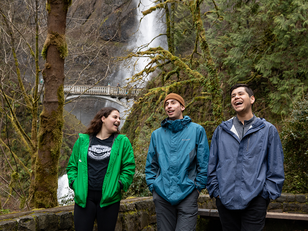 Three Oregon students stand in front of a large waterfall at the Columbia River Gorge