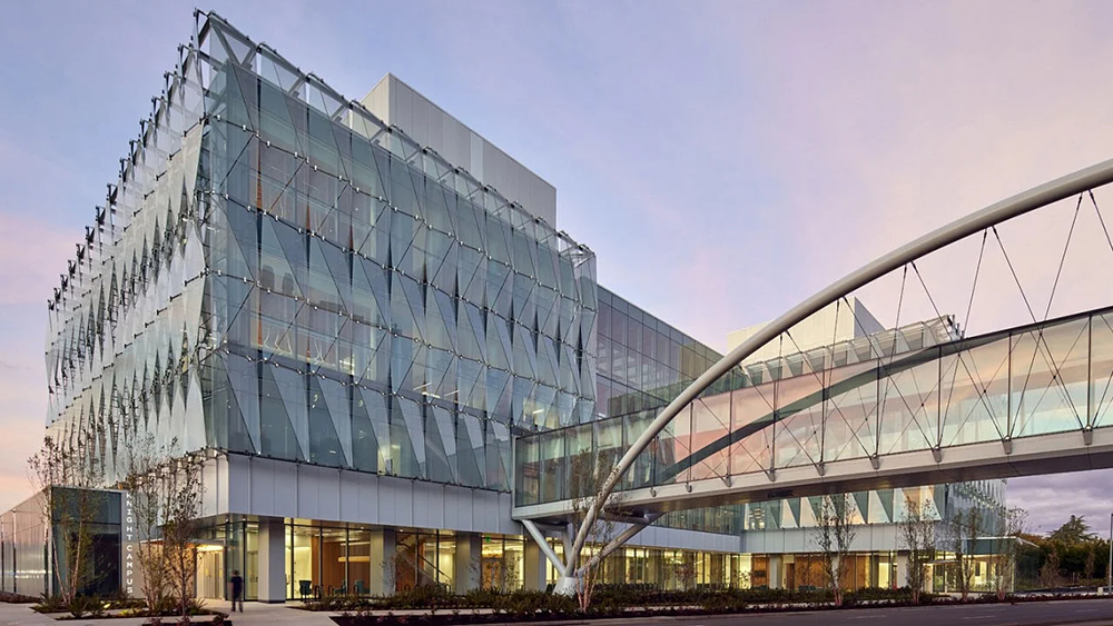 The Knight Campus glass building and arched skybridge at dusk.