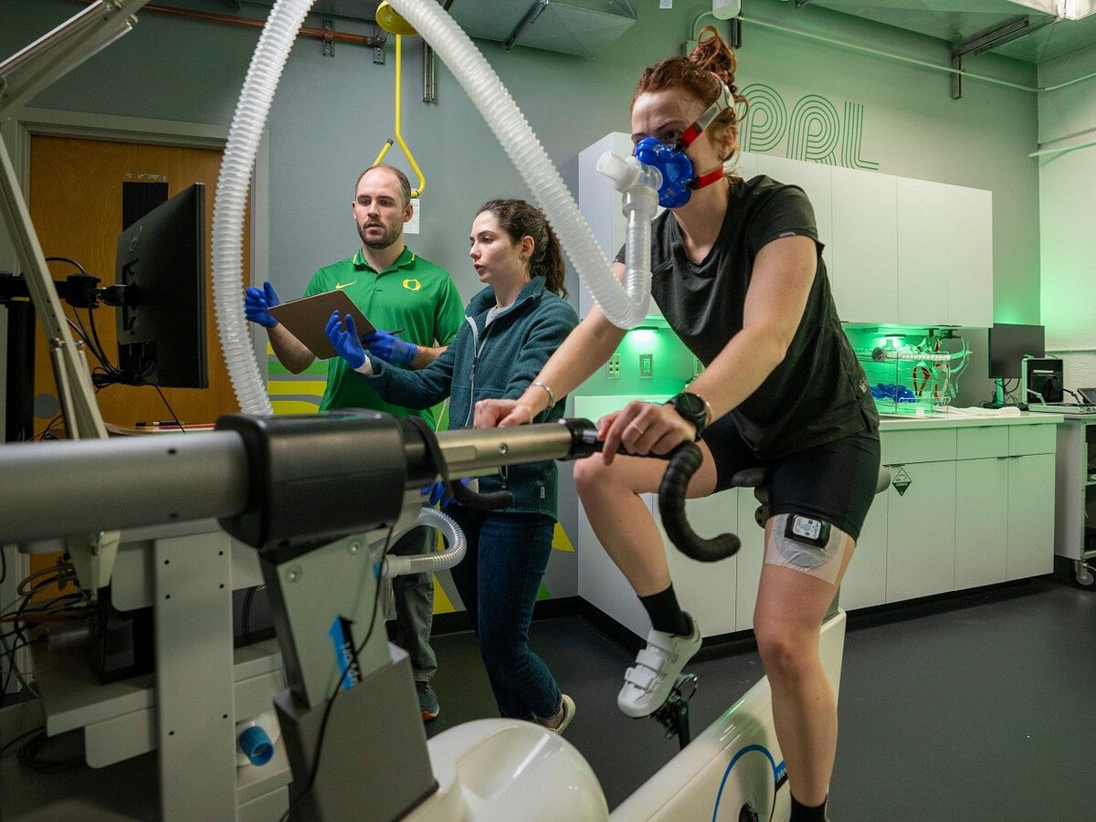 Researchers monitor an athlete cycling in a performance laboratory.