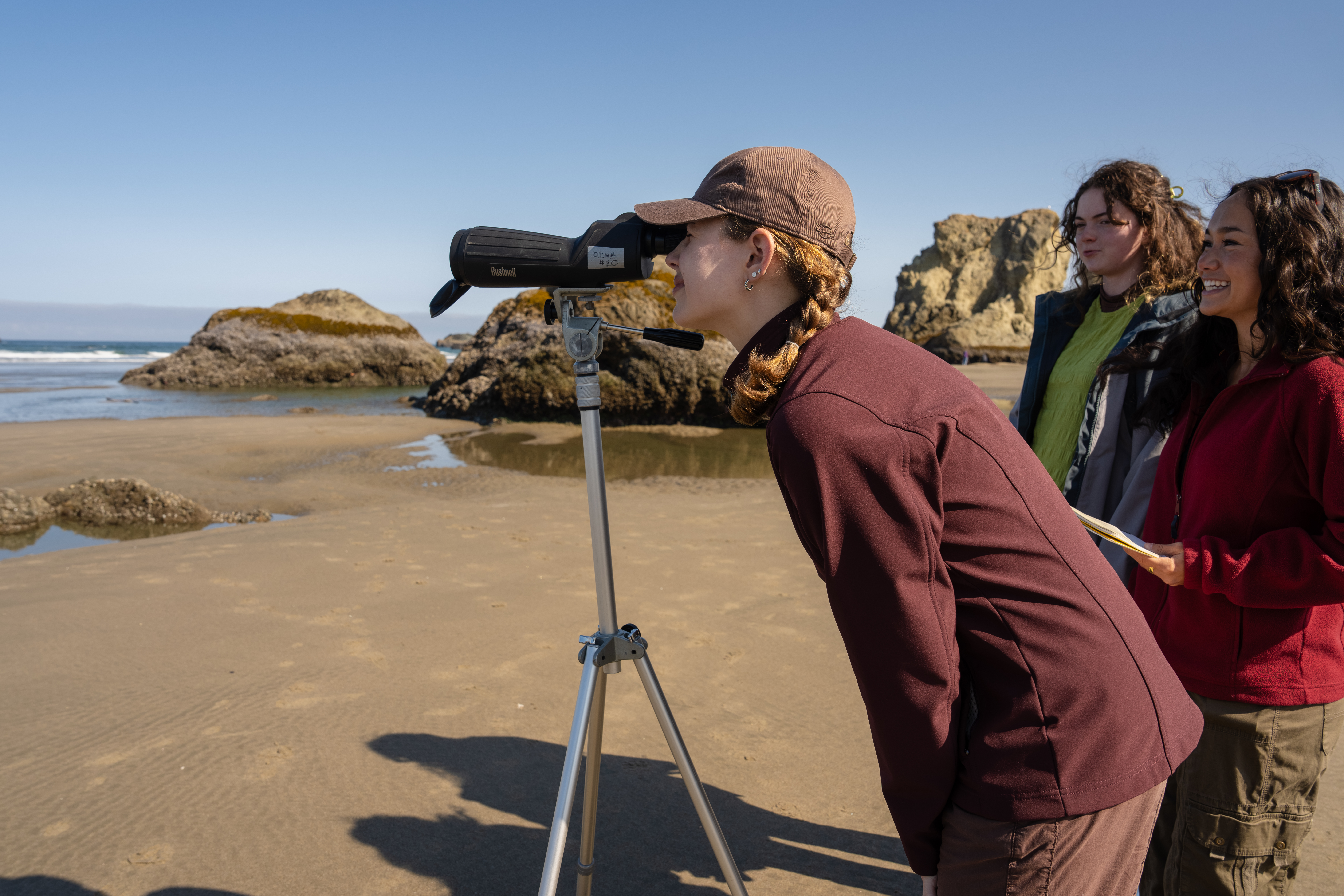 Marine Biology student looking through an industrial scope at the coast