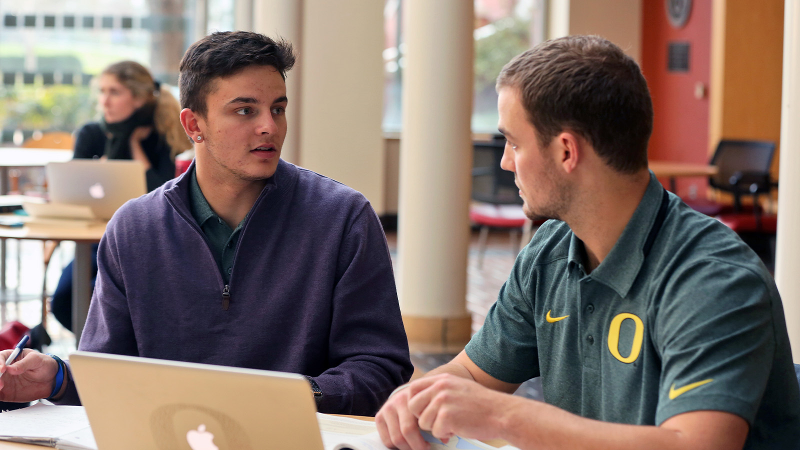 two students sitting at table with laptop collaborating on a project
