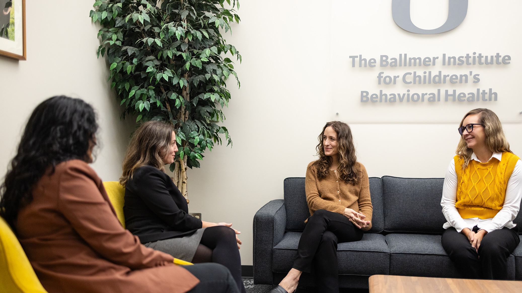 Four people sit talking in a Ballmer Institute lounge.