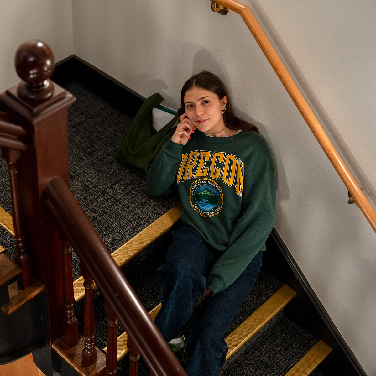 A student in an Oregon sweatshirt sits on a staircase.