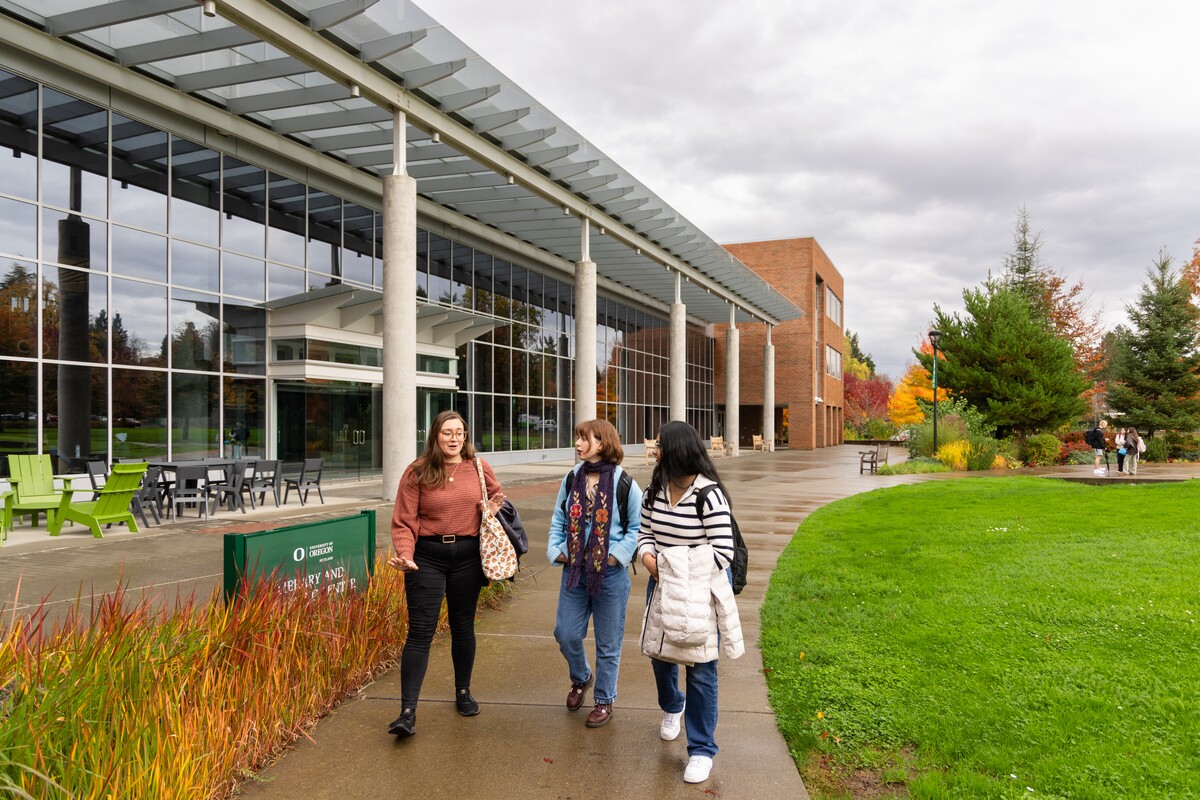 Three students walk outside a University of Oregon campus building.