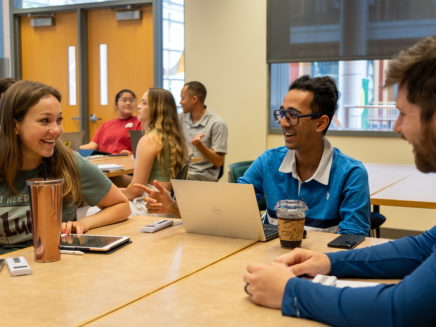 Three students laughing and talking at a table.