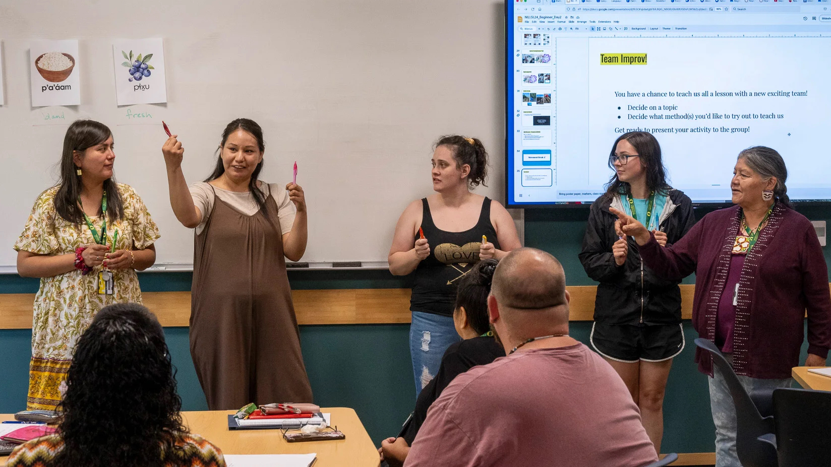 Instructor holding up a pen in front of a classroom