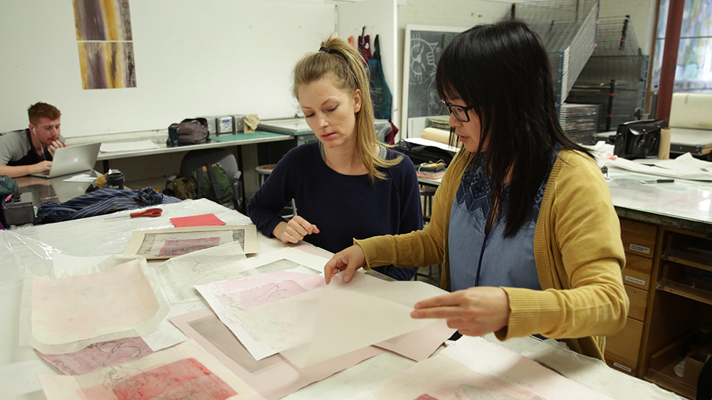 Two students reviewing documents in art class