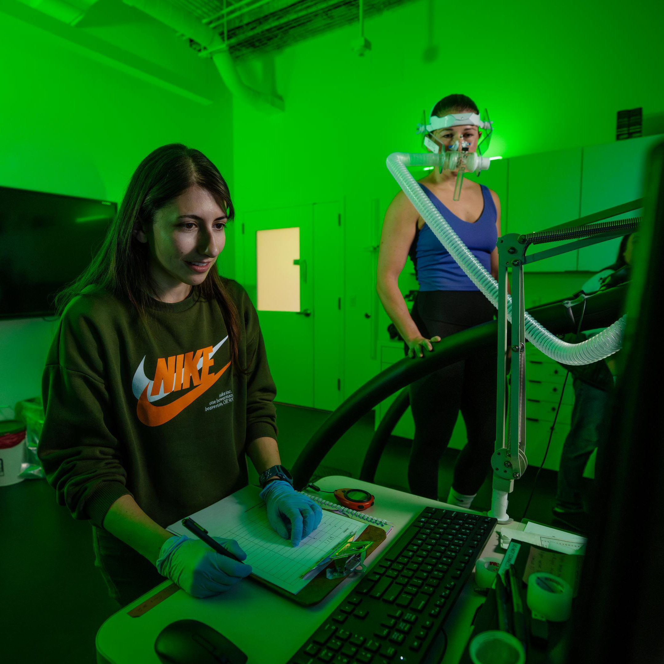 A student recording numbers in a lab next to a runner