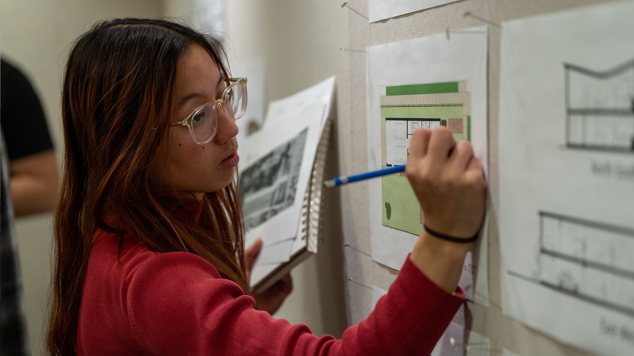 A student reviews a site plan pinned to a wall