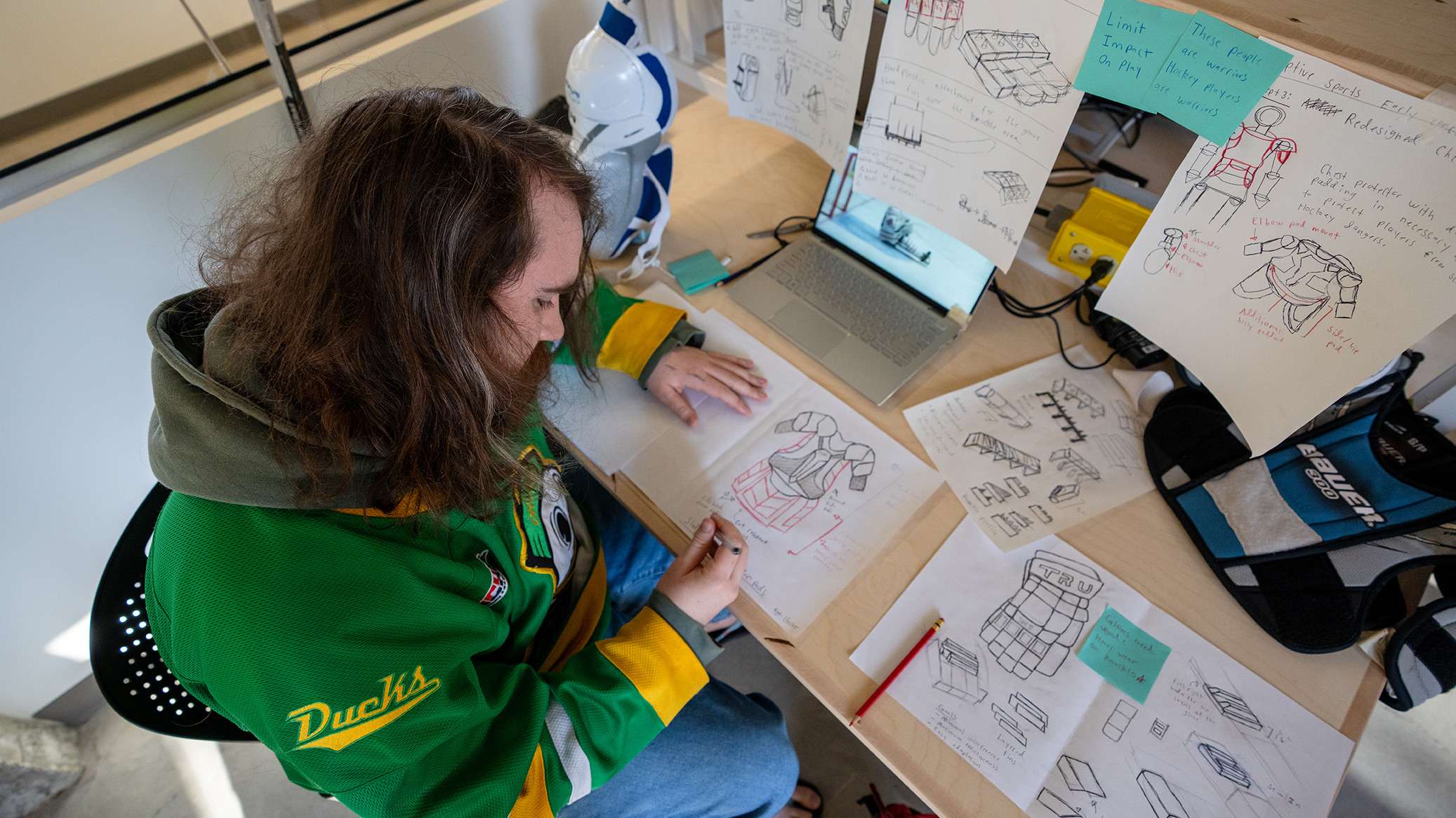 A student sketches sports product designs at a studio desk
