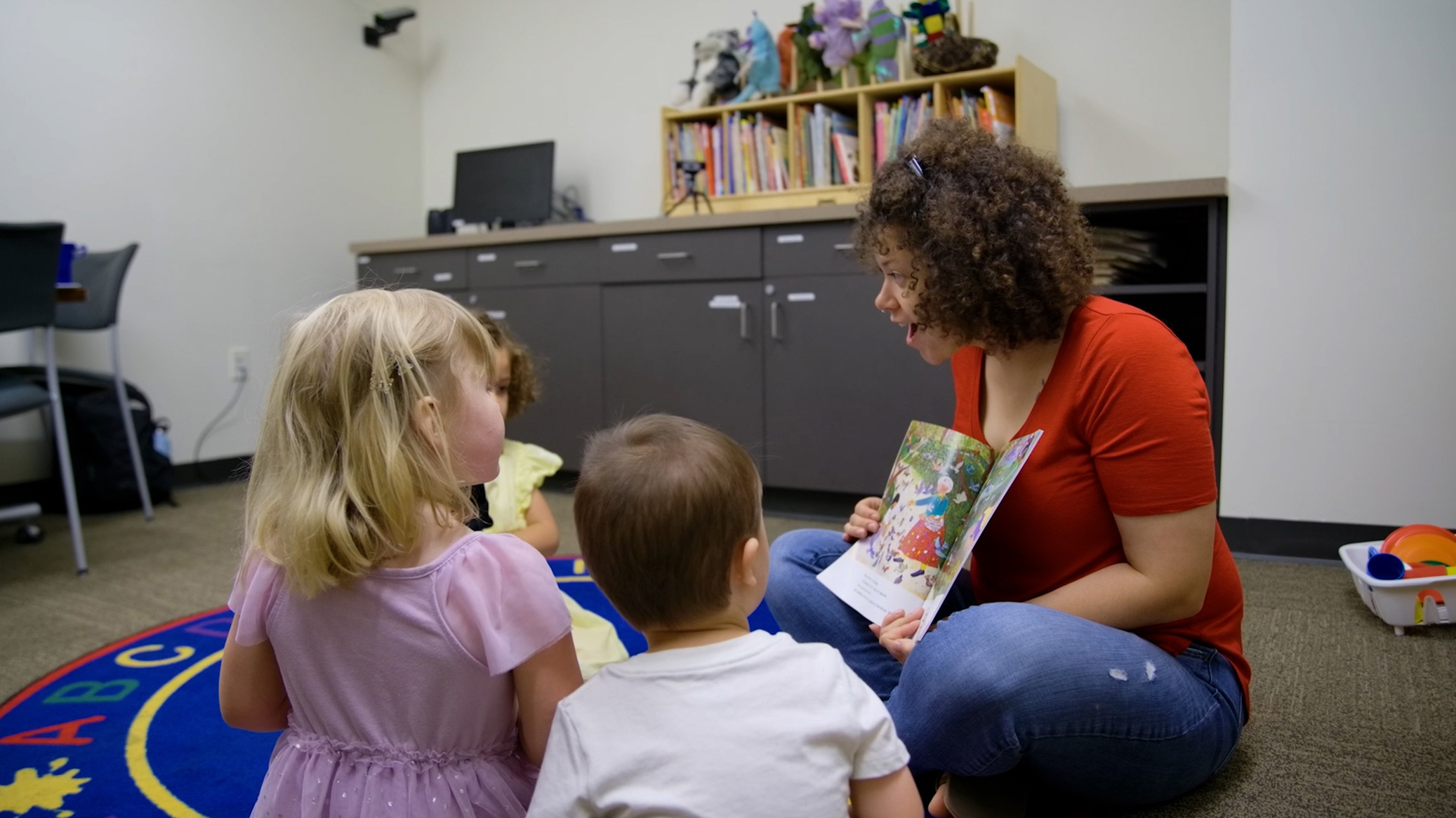 A teacher holding up a book in front of children