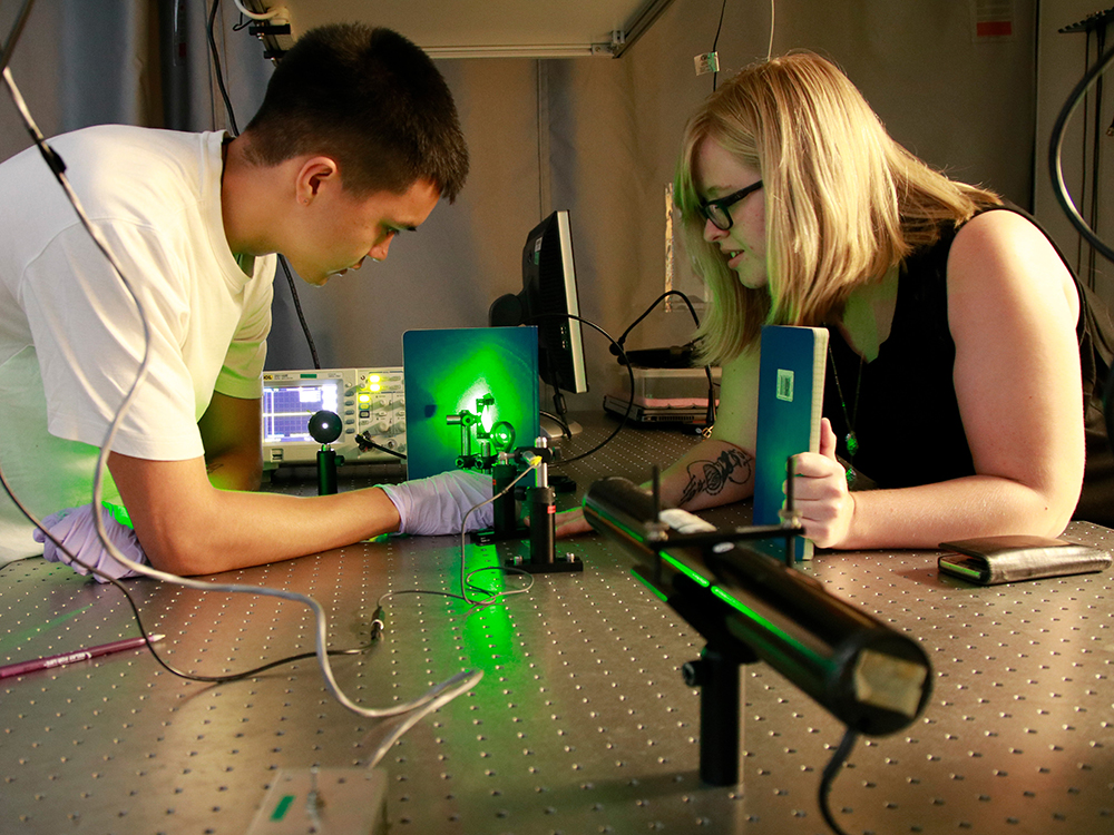 Two students using a laser in a lab