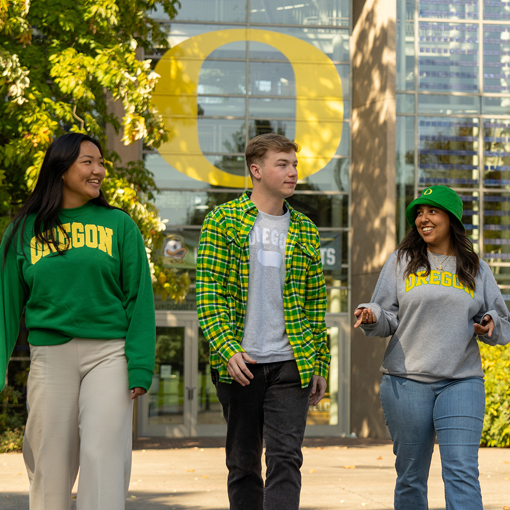 Three students walking in front of the Lundquist College of Business