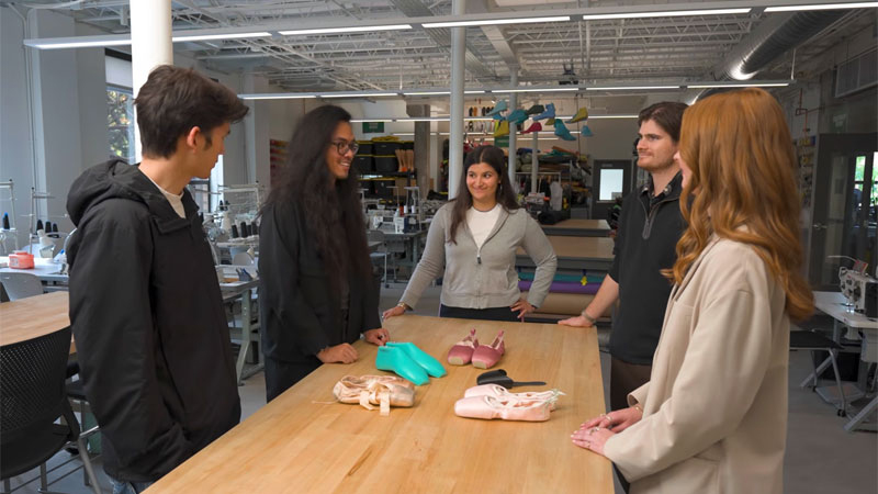 Studnts standing at a table with shoe prototypes on it
