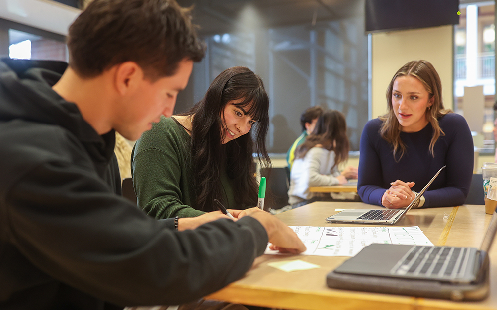 Three students chatting at a table
