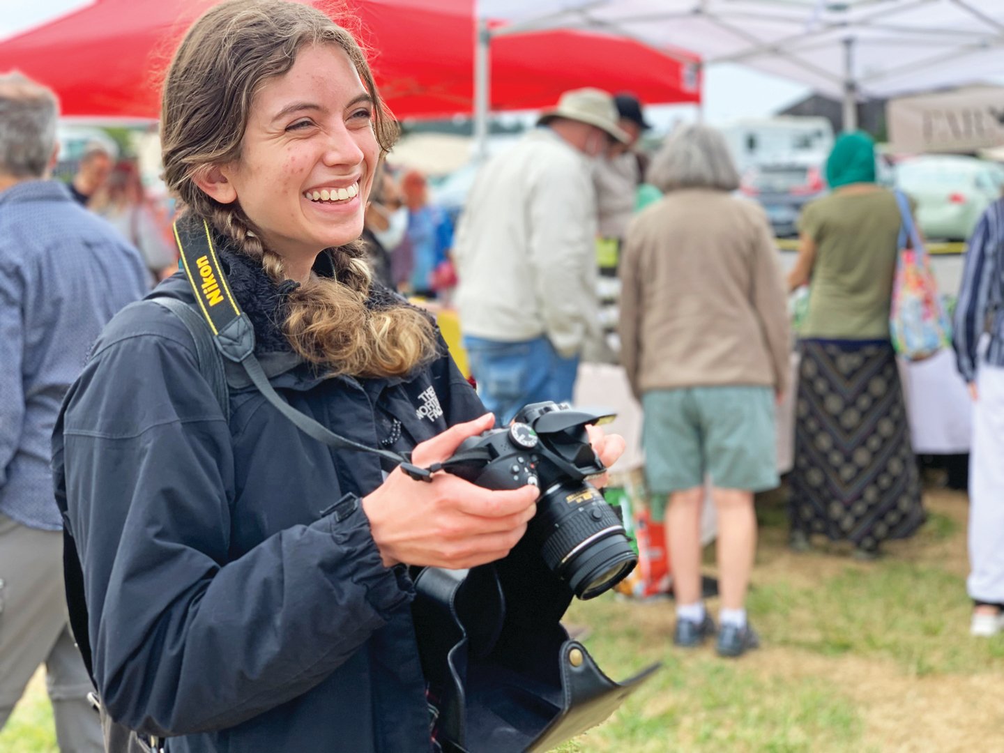 Student smiling and holding a camera