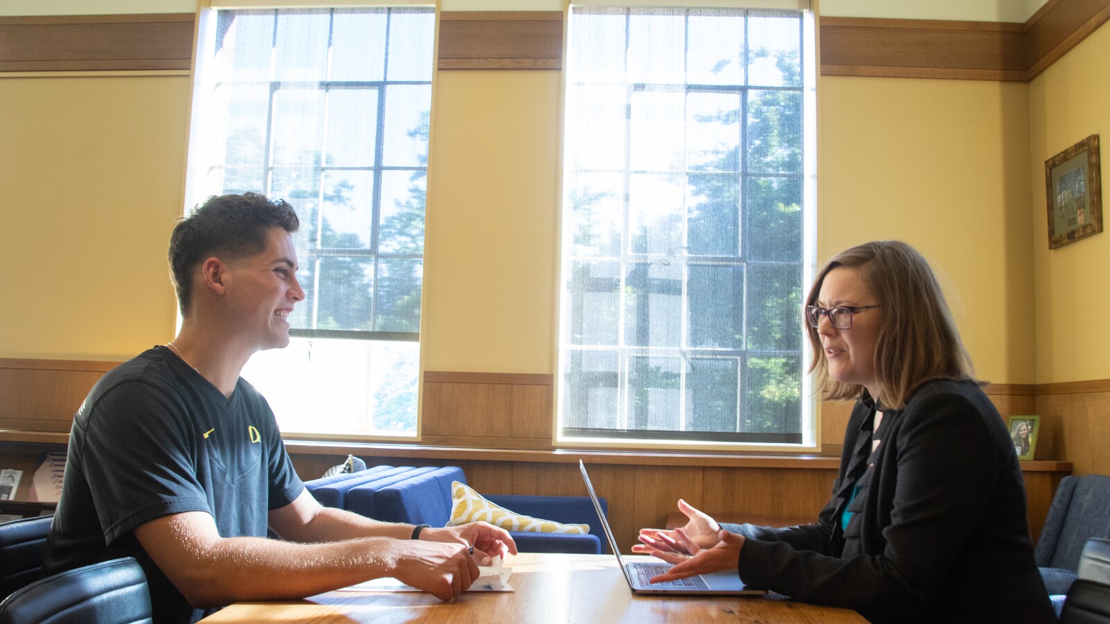 A student meets with an academic advisor across a table.