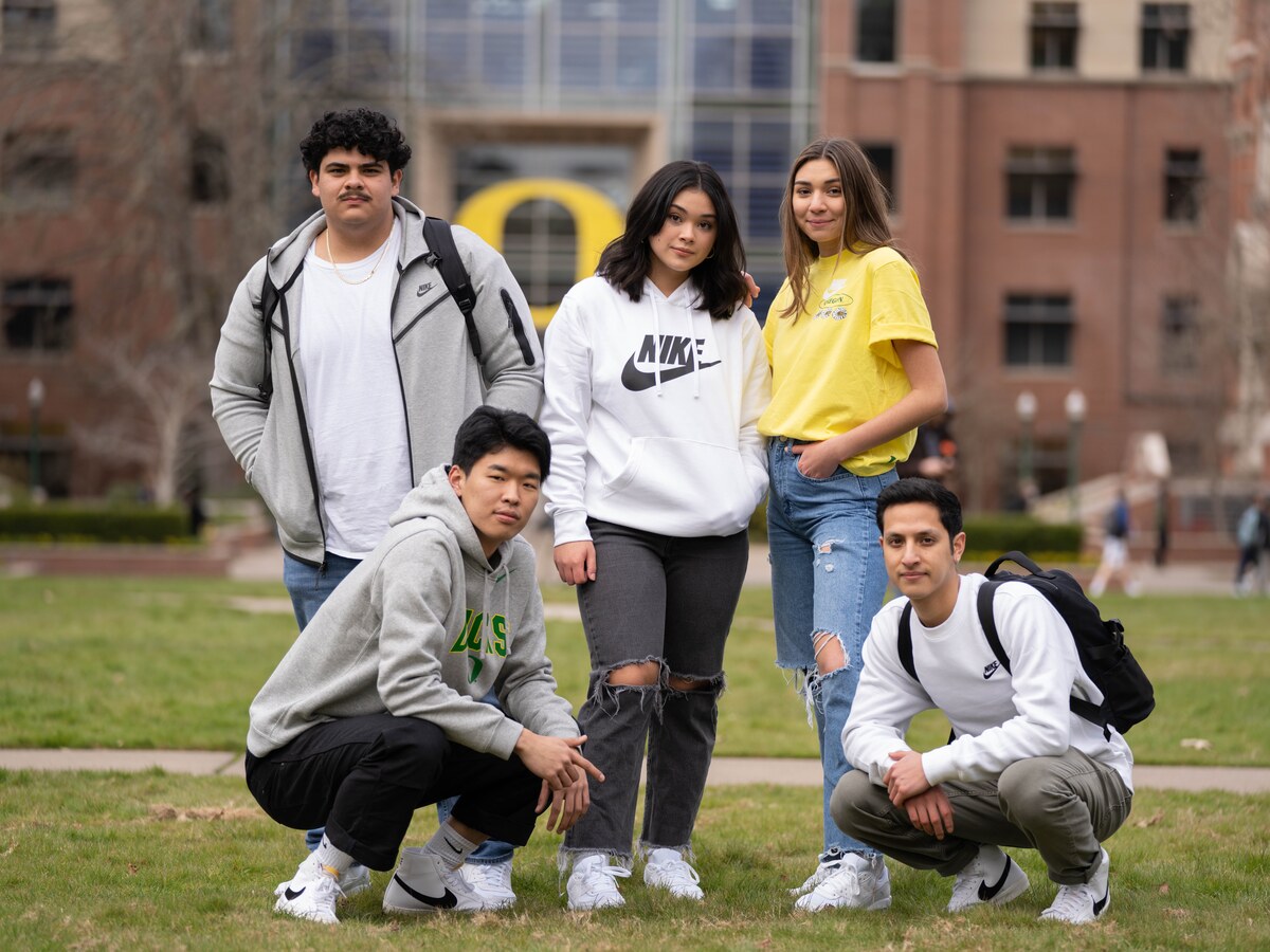 Five students pose together outside on campus.
