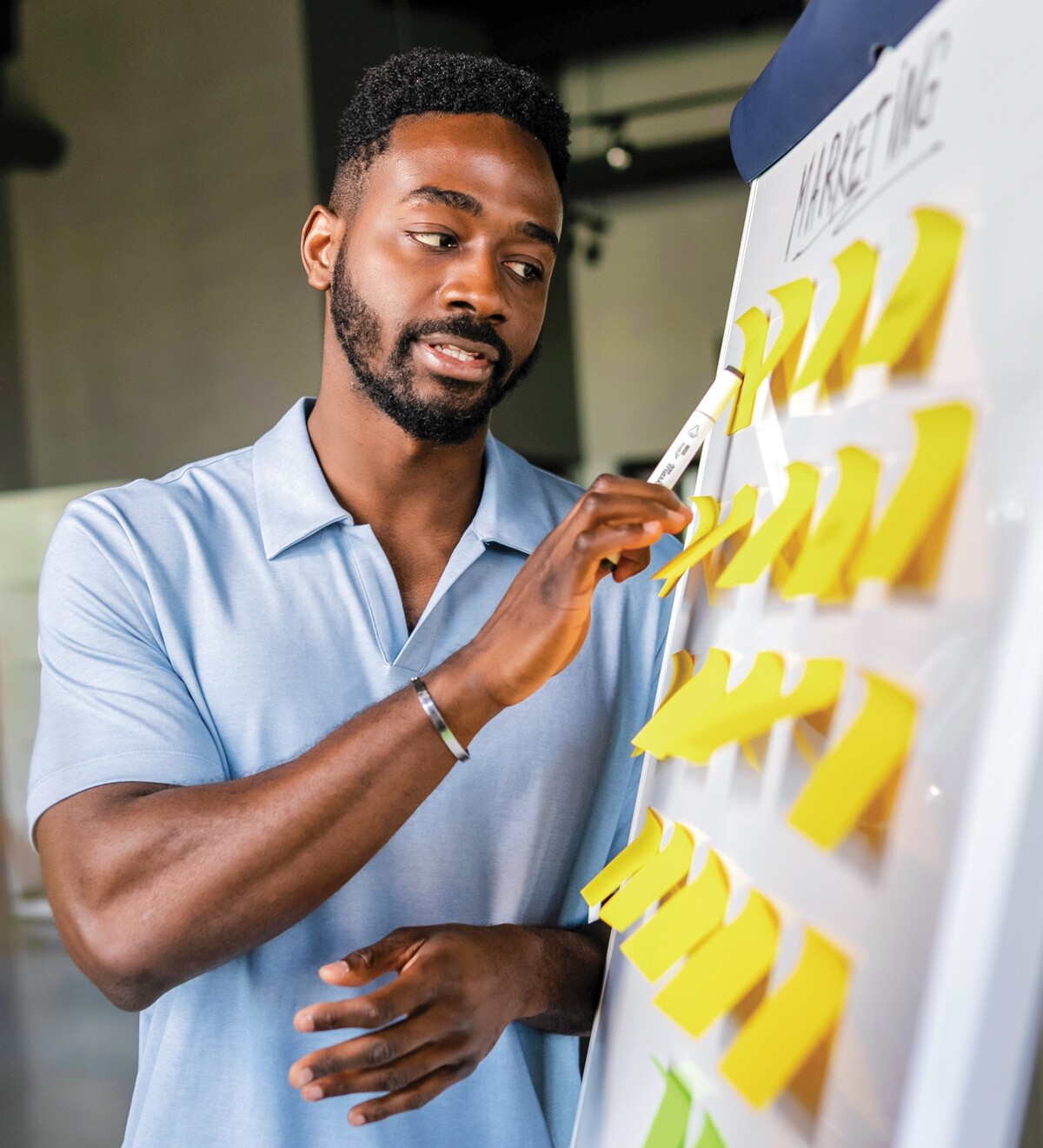 A young man arranges yellow notes on a presentation board.