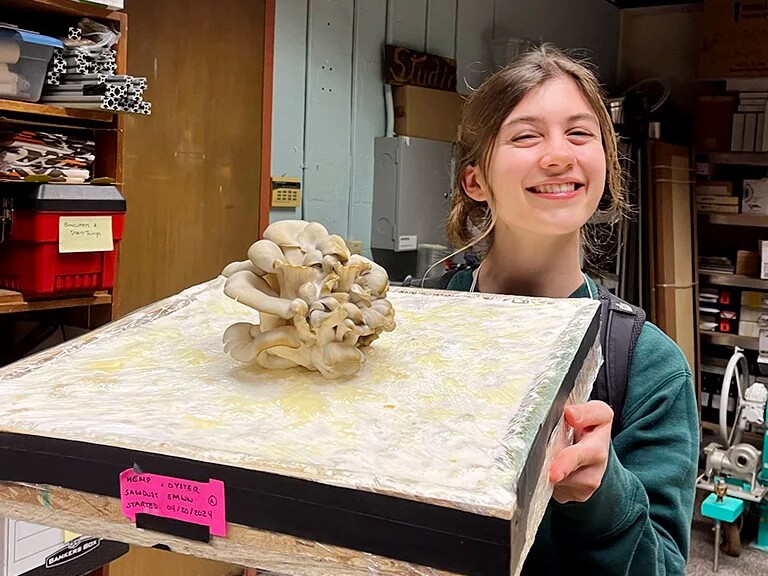 Charlotte Kamman holds a mushroom-covered acoustic panel in a workshop.