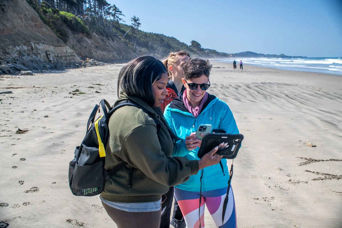 Kea Powell shows a tablet to a visitor on the Oregon coast.