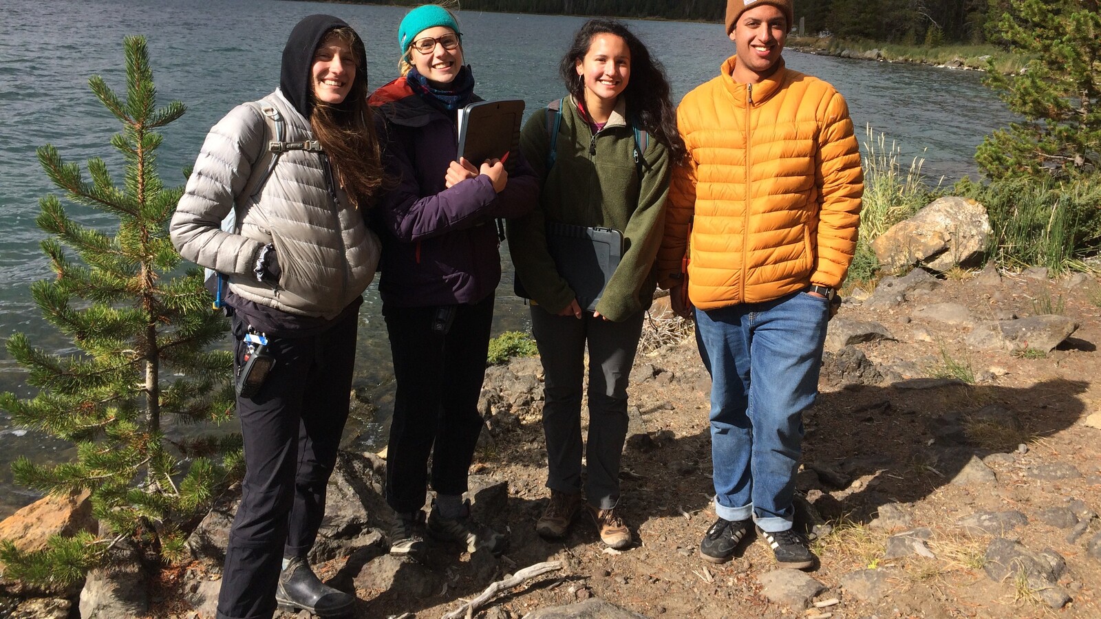 Four students gather beside a mountain lake.