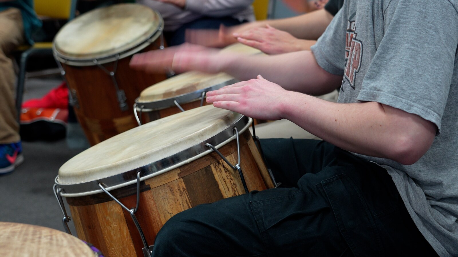 Students play drums together in a world music class.