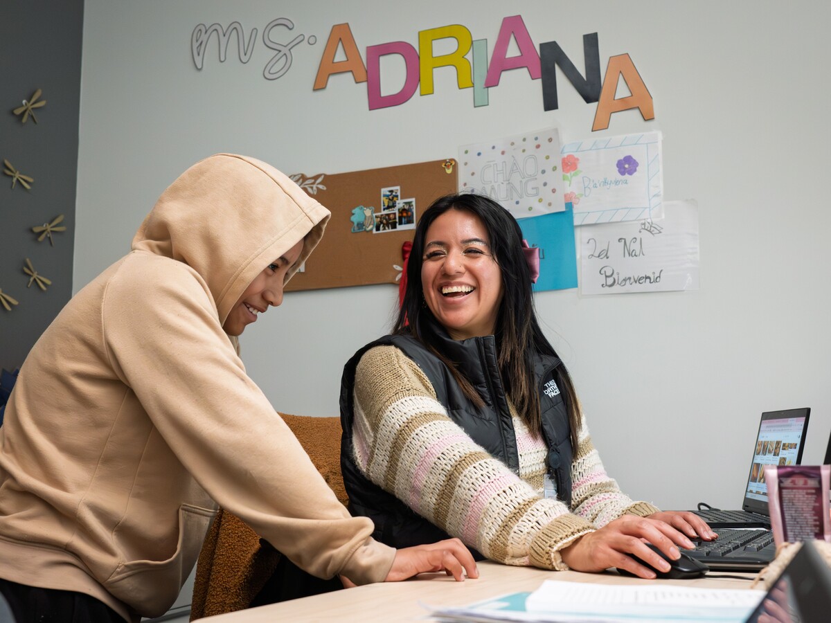 An adult and child smile while working at a computer.
