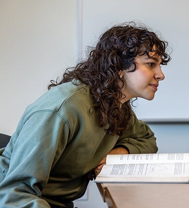 A student studies an open book in a classroom.
