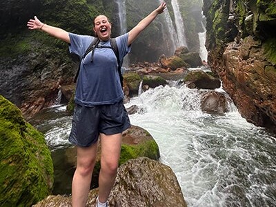 A student stands beside a waterfall in Costa Rica.