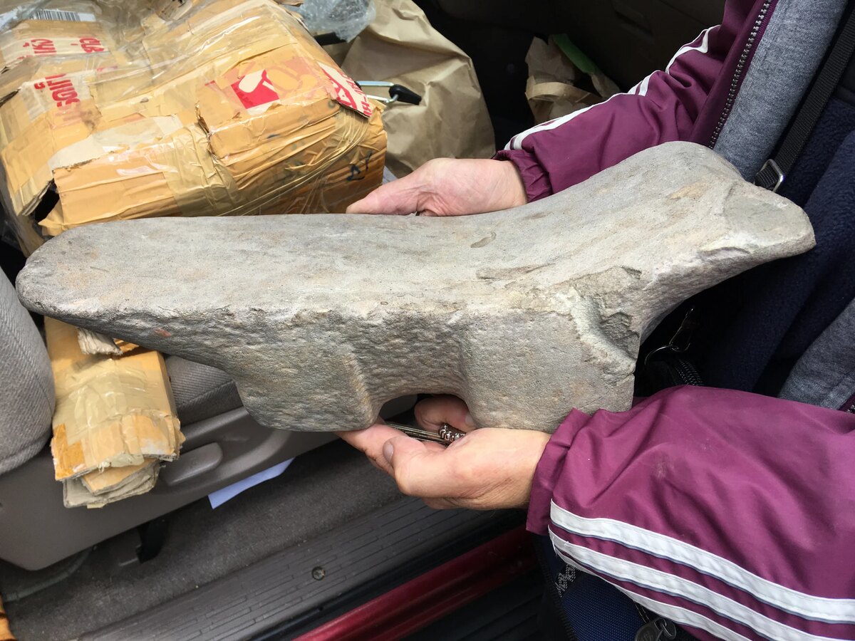 Hands hold an ancient carved stone artifact.