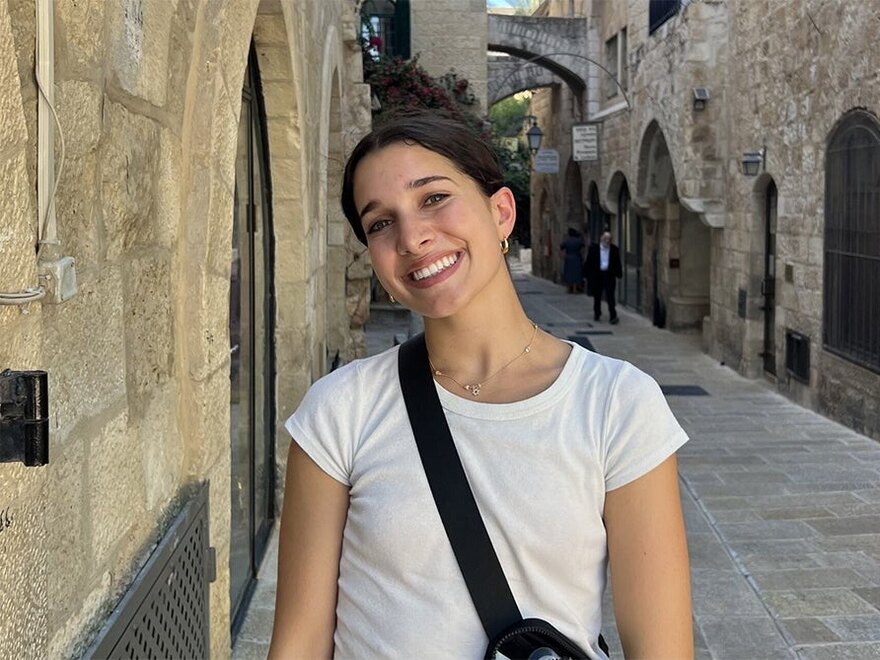 Talia James smiles on a stone-lined street.