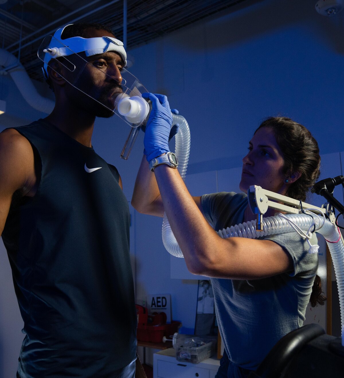 A researcher adjusts breathing equipment on an athlete.