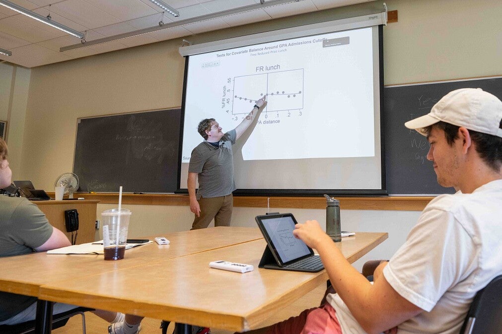 An instructor points to a graph during a classroom lesson.