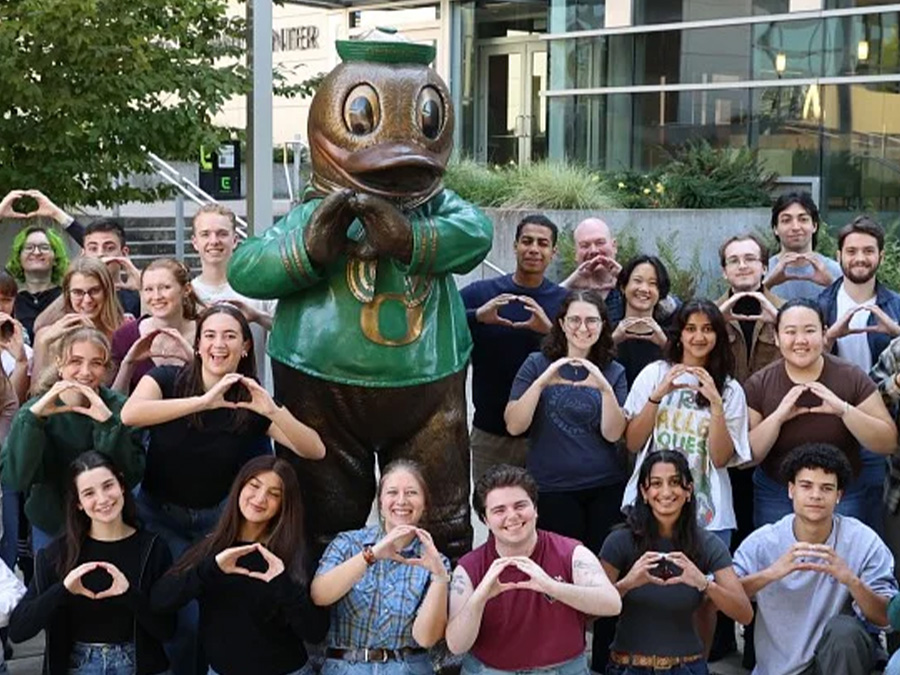 Wayne Morse Scholars gather with the Oregon Duck outside a campus building.