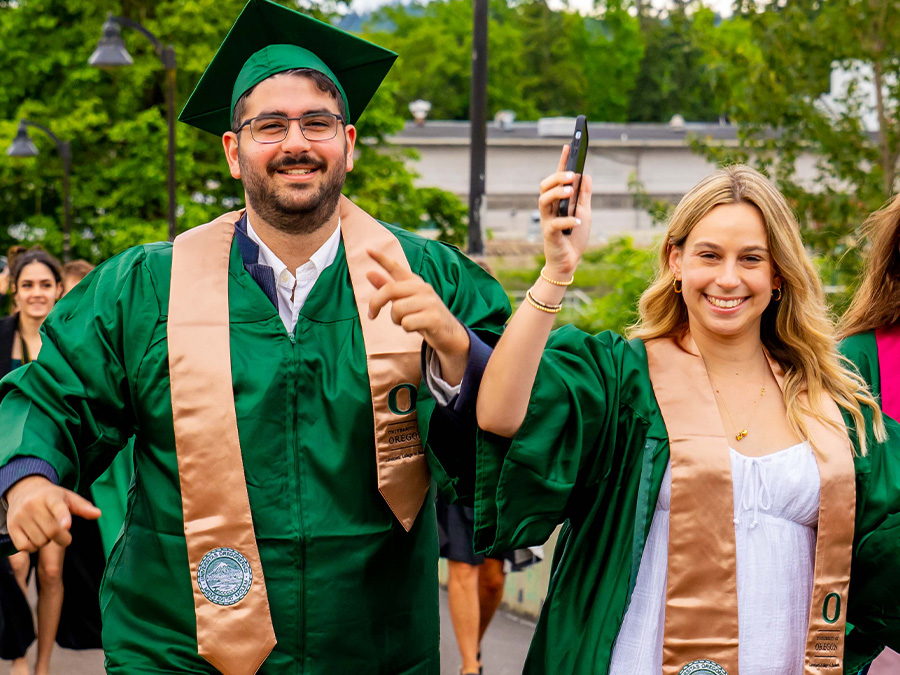 Two students crossing the Autzen bridge on their way to commencement