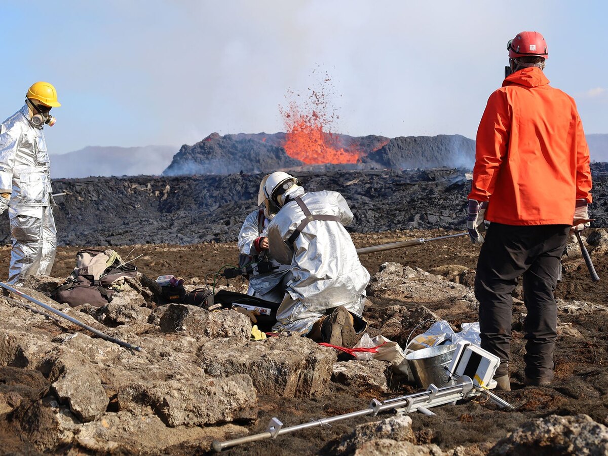 Researchers collect samples near an active volcanic eruption.