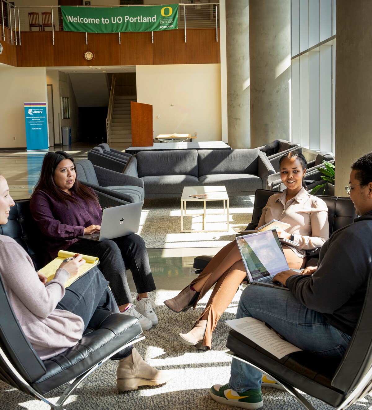 Four people meet with laptops in a UO Portland lounge.