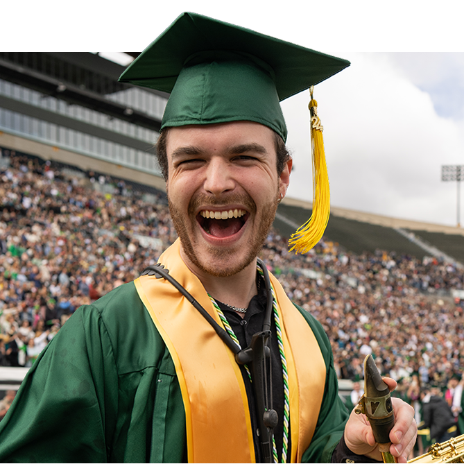 Smiling graduate in a green cap and gown.