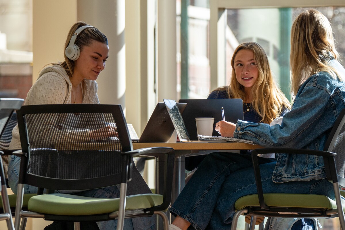 Three students study together at a table.