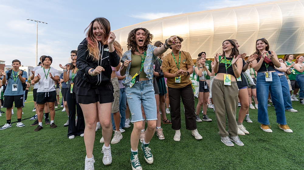 New students dancing together during IntroDucktion in front of Hayward Field