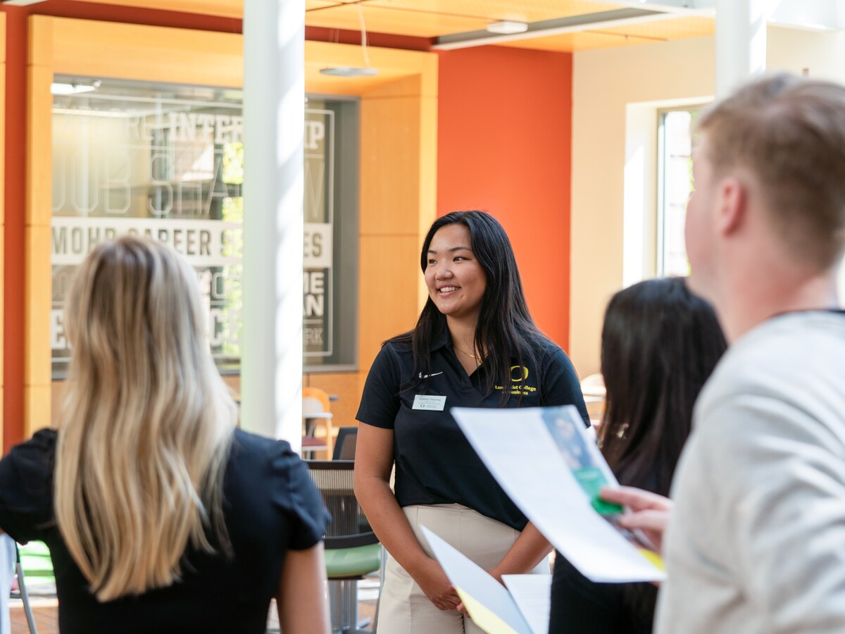 A student guide speaks with visitors inside the Lillis Business Complex.