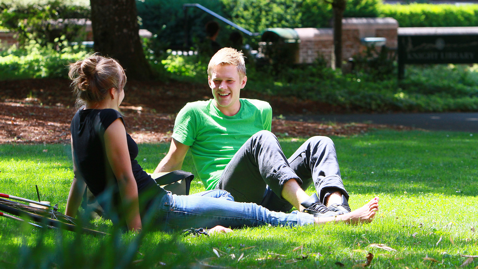 two student sitting on a green campus lawn