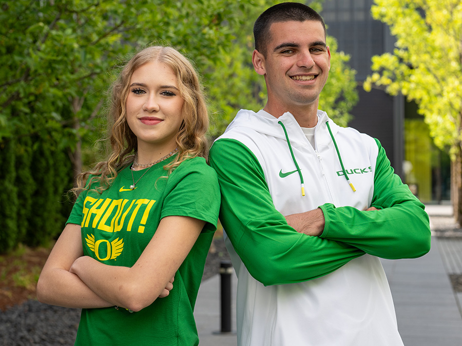 two students wearing UO branded clothing, smiling towards camera