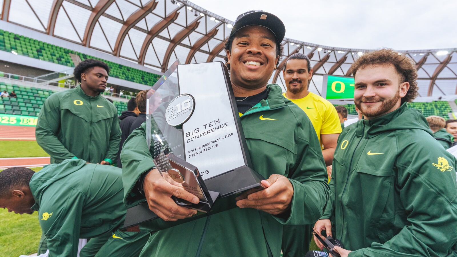 Oregon track athletes celebrate with a Big Ten championship trophy.