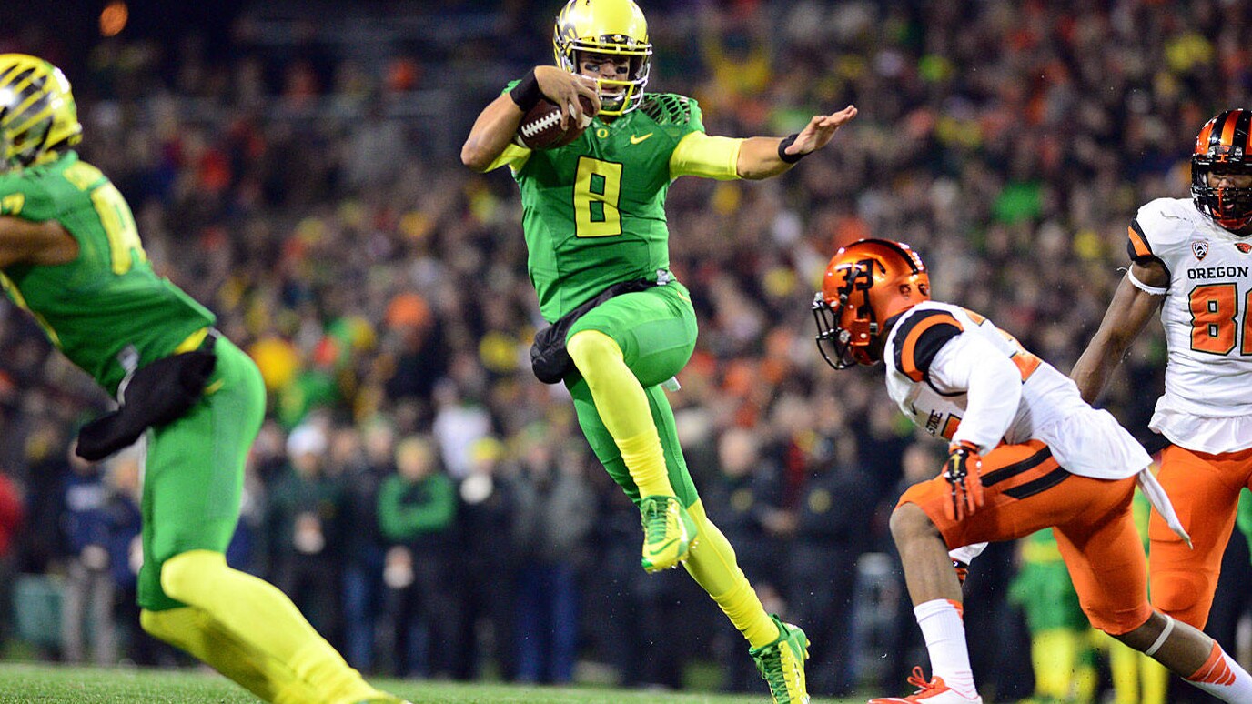 Marcus Mariota leaps past defenders during Oregon’s 2014 football season.