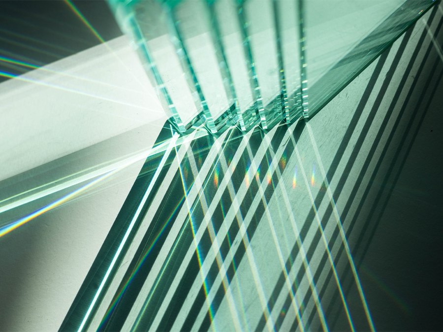 Glass sheets cast geometric shadows and prismatic light across a surface.