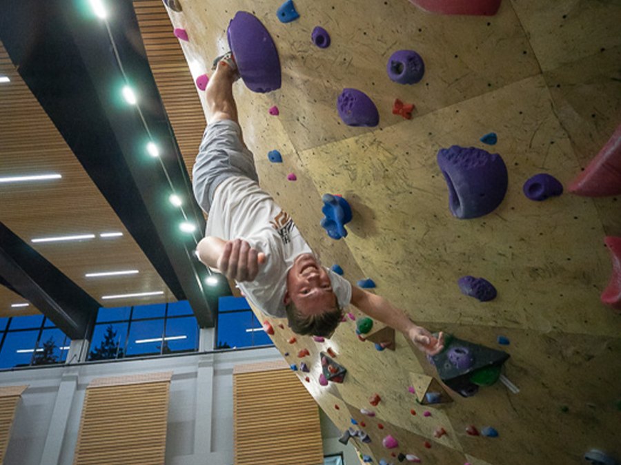 A climber reaches across an overhanging indoor bouldering wall.